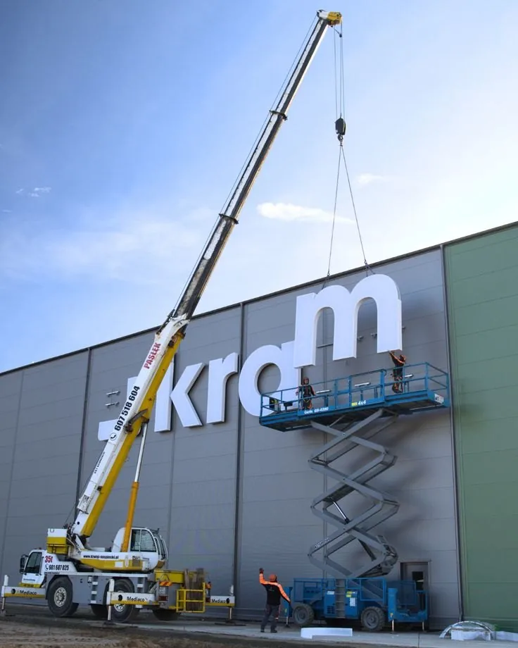 Crane lifting illuminated letters onto a building