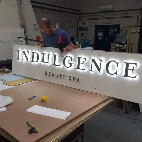 Sign maker finishing a halo-lit sign in the workshop